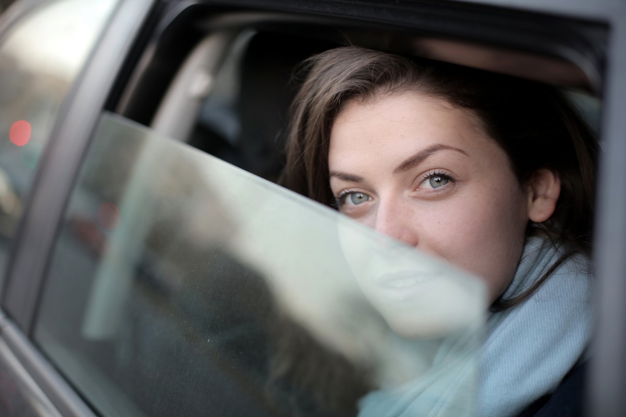 Analiza kolorystyczna i odwaga - młoda kobieta, która uchyla okno w samochodzie - jej oczy widać wyraźnie, pół twarzy pozostaje schowane za szybą.